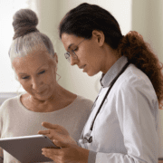 A female patient reviewing her digital health records on a tablet with a female doctor.